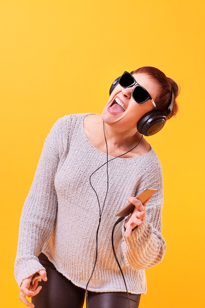 Mujer mayor feliz escuchando música y bailando