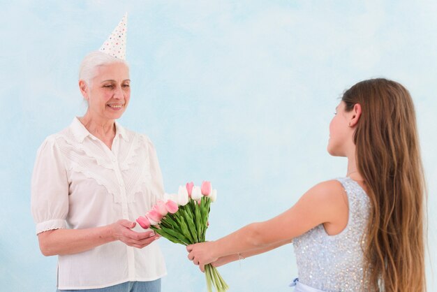 Mujer mayor feliz recibiendo ramo de flores de tulipán de su nieto