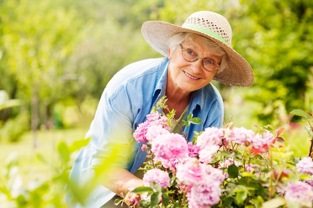 Mujer mayor, con, flores, en, jardín