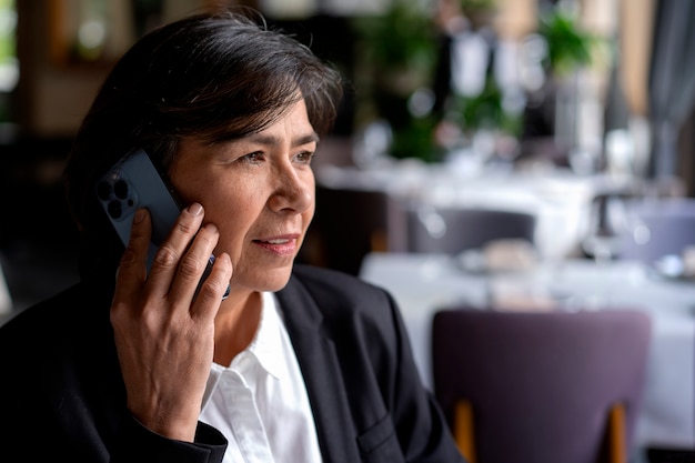 Foto gratuita mujer mayor hablando por teléfono inteligente en un restaurante de lujo