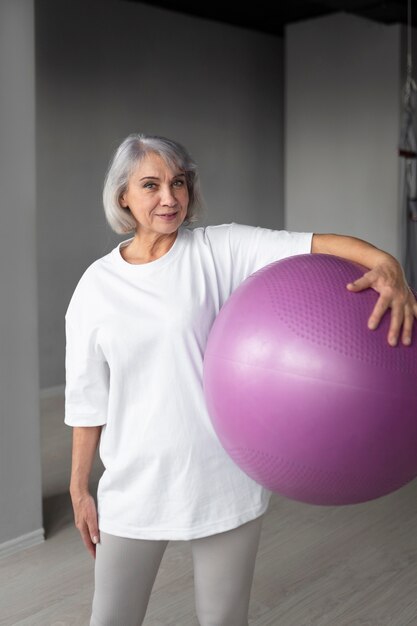 Mujer mayor haciendo ejercicios de pelota de gimnasia en el gimnasio