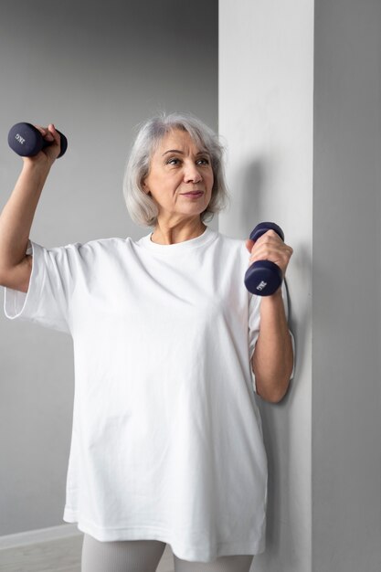 Mujer mayor haciendo ejercicios de pesas en el gimnasio