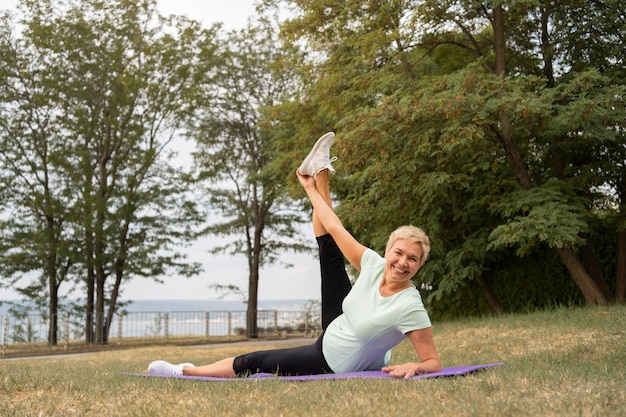 Mujer mayor haciendo yoga al aire libre en el parque