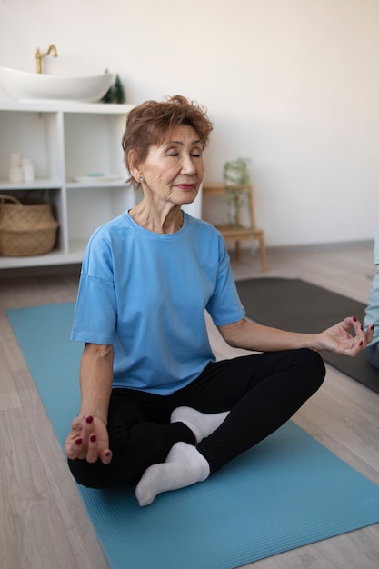 Mujer mayor haciendo yoga en casa