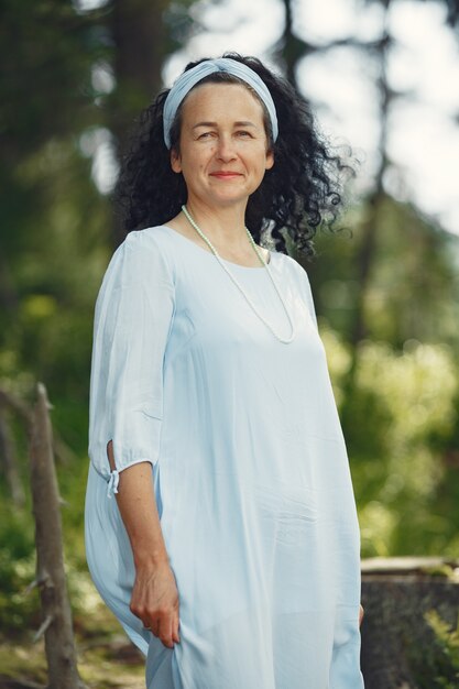 Mujer mayor mira a la cámara. Dama con un vestido azul. Morena camina.