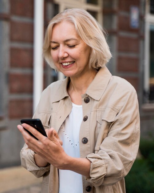 Mujer mayor mirando smartphone mientras está en la ciudad