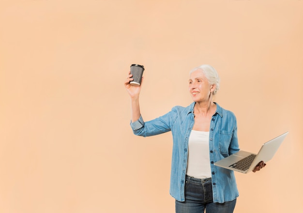 Mujer mayor moderna con portátil y café