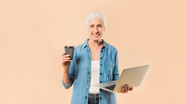 Mujer mayor moderna con portátil y café