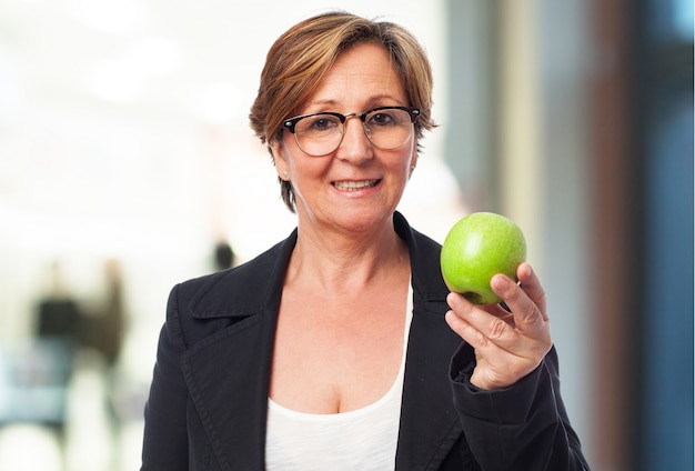 Mujer mayor de negocios sujetando una manzana