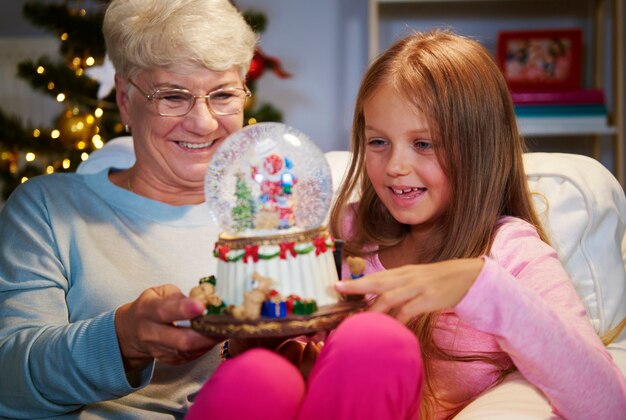 Mujer mayor con nieta sosteniendo una decoración navideña