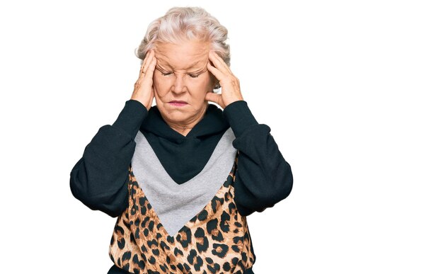 Foto gratuita mujer mayor de pelo gris con ropa deportiva que sufre de dolor de cabeza desesperada y estresada porque el dolor y la migraña tienen las manos en la cabeza