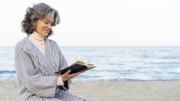 Mujer mayor, en la playa, lectura, un, libro