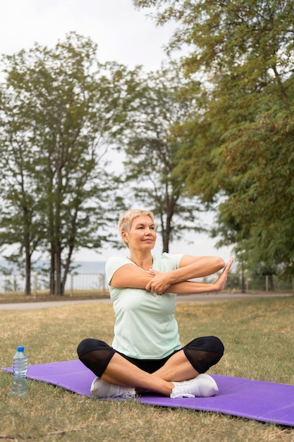 Mujer mayor practicando yoga al aire libre en el parque