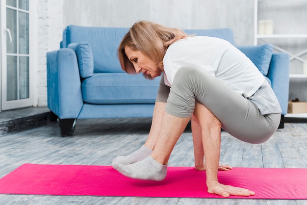 Mujer mayor practicando yoga en casa