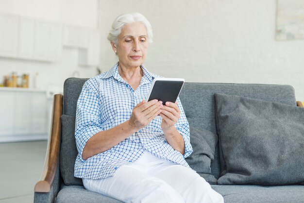 Mujer mayor que mira la tableta digital