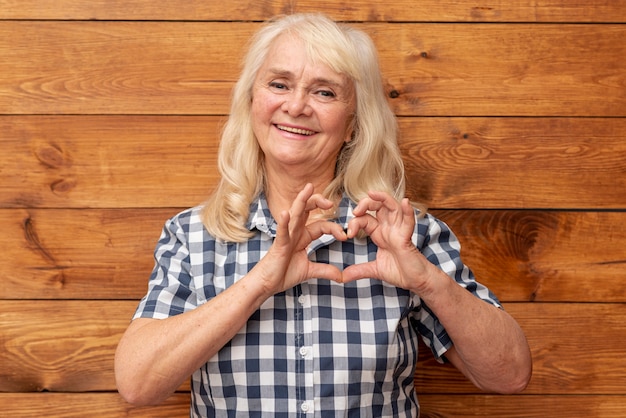 Mujer mayor que muestra forma del corazón con las manos