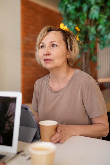 Mujer mayor que pasa tiempo en un café y trabaja en su tableta