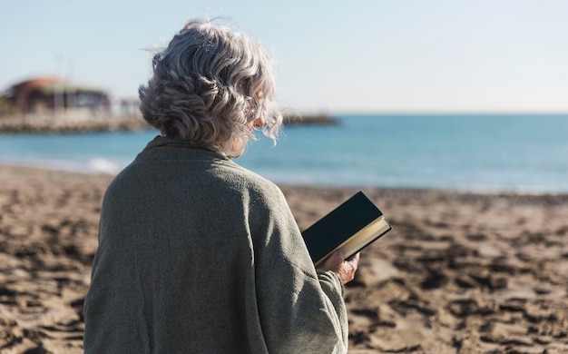 Mujer mayor que sostiene la opinión trasera del libro