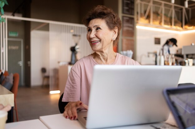 Mujer mayor que trabaja en su computadora portátil en un café