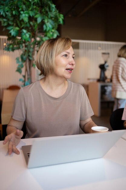 Mujer mayor que trabaja en su computadora portátil en un café