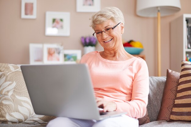Mujer mayor, relajante, con, computador portatil, en, sofá