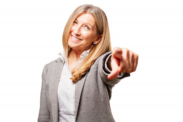 Mujer mayor señalando hacia el frente y sonriendo