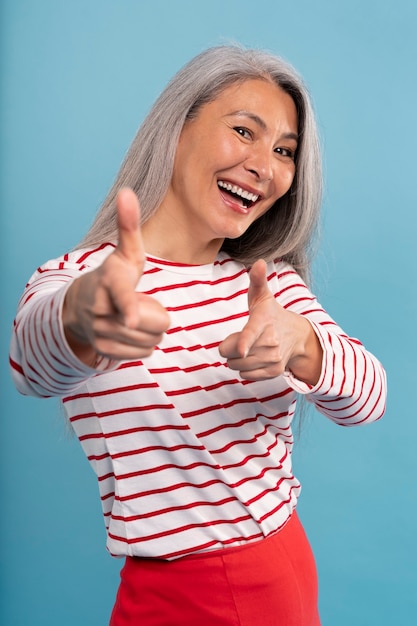 Foto gratuita mujer mayor, señalar, contra, un, fondo azul