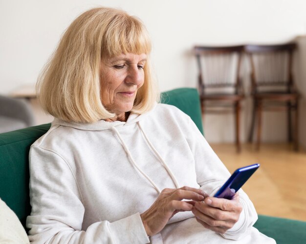 Mujer mayor con smartphone en casa