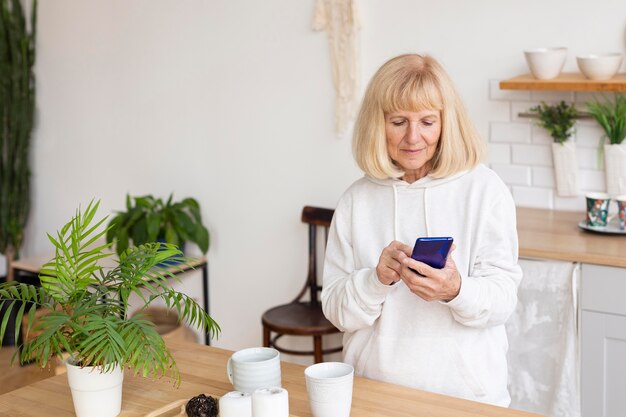 Mujer mayor con smartphone en casa