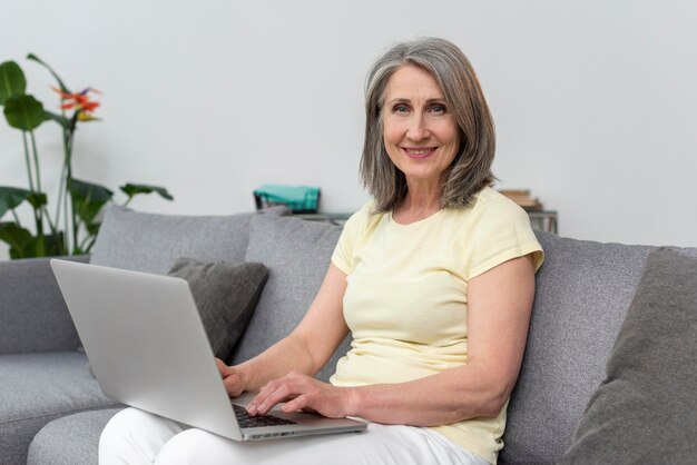 Mujer mayor, en el sofá, en casa, usar la computadora portátil