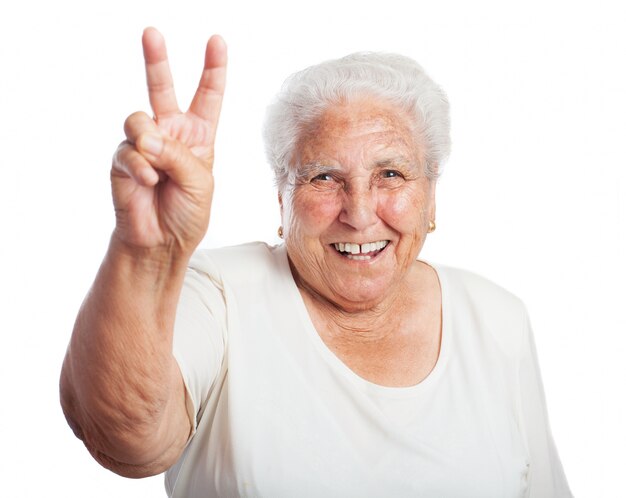 Mujer mayor sonriendo con dos dedos levantados