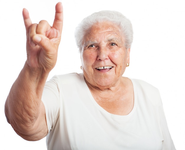 Mujer mayor sonriendo haciendo los cuernos con la mano