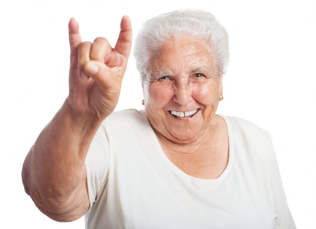 Mujer mayor sonriendo haciendo los cuernos con la mano