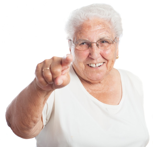 Mujer mayor sonriendo señalando hacia el frente