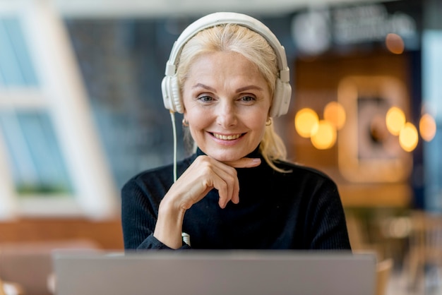 Mujer mayor sonriente en una conferencia con auriculares