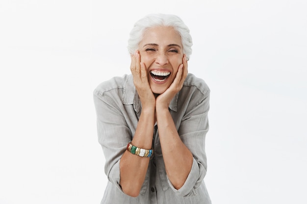 Foto gratuita mujer mayor sonriente despreocupada mirando feliz, tocando la cara