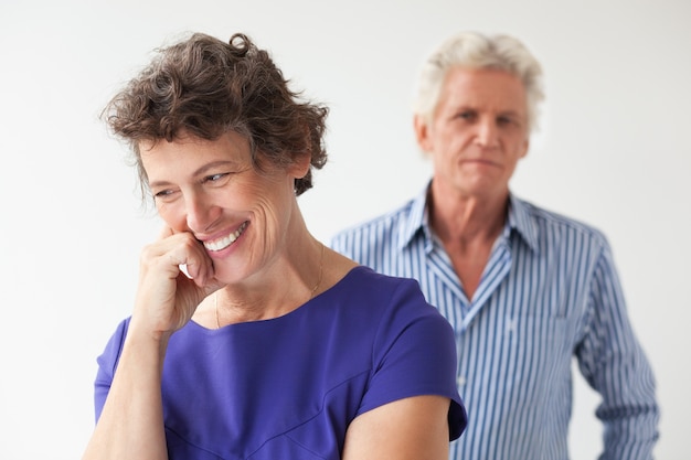 Mujer mayor sonriente y marido de pie detrás