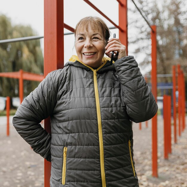 Mujer mayor sonriente tomando el teléfono al aire libre