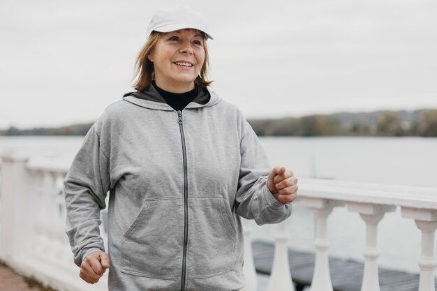 Mujer mayor sonriente trotar al aire libre