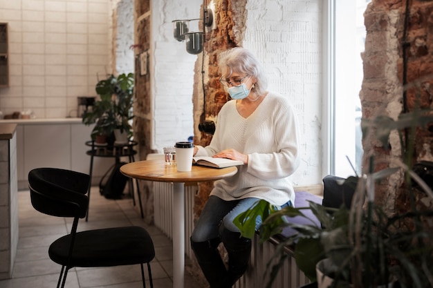 Foto gratuita mujer mayor de tiro completo leyendo en el interior