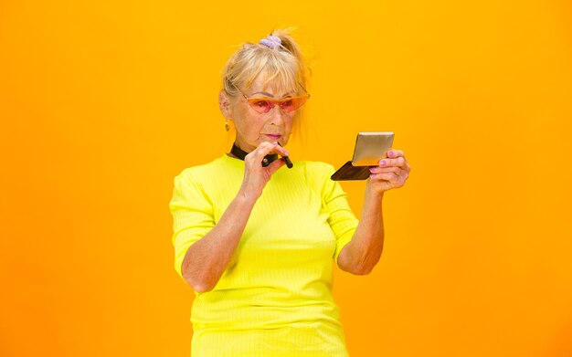 Mujer mayor en traje ultra moderno aislado en naranja brillante