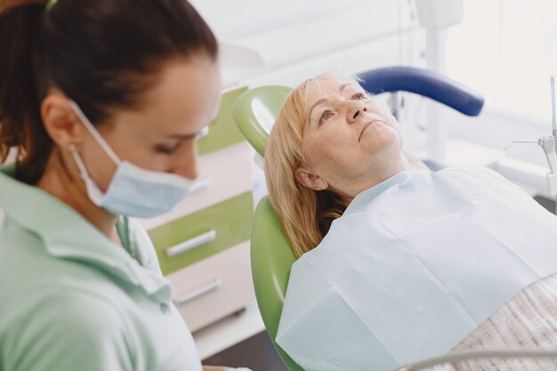 Mujer mayor con tratamiento dental en el consultorio del dentista. La mujer está siendo tratada por los dientes