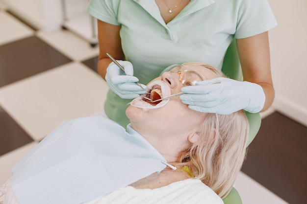 Mujer mayor con tratamiento dental en el consultorio del dentista. La mujer está siendo tratada por los dientes