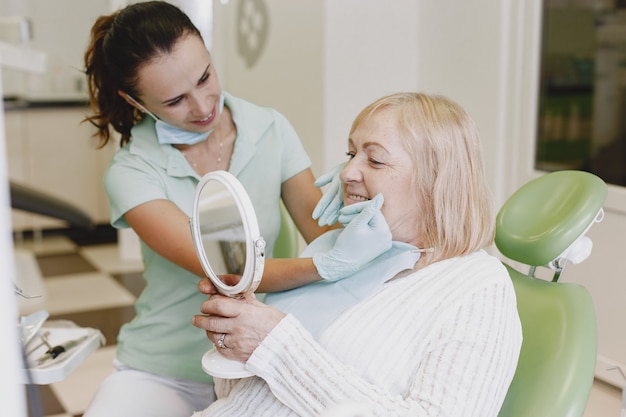 Mujer mayor con tratamiento dental en el consultorio del dentista. La mujer está siendo tratada por los dientes