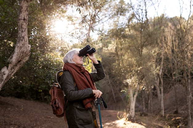 Mujer mayor usando binoculares durante una caminata por la naturaleza