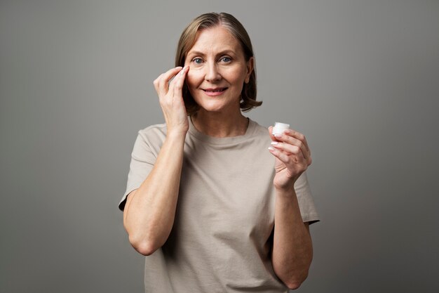 Mujer mayor usando crema facial de tiro medio