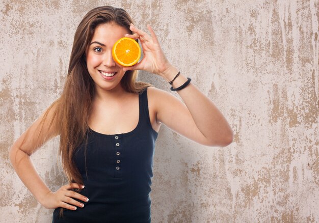 Mujer con media naranja en un ojo