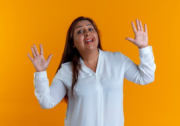 Mujer de mediana edad caucásica casual sorprendida extiende las manos aisladas en la pared amarilla