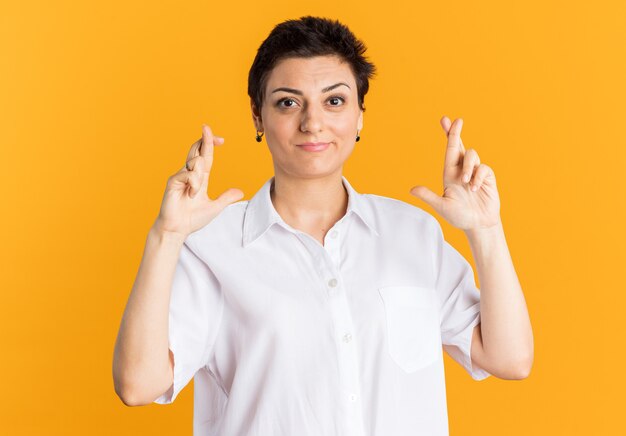 Mujer de mediana edad complacida mirando a la cámara haciendo gesto de buena suerte