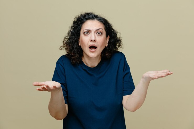 Foto gratuito mujer de mediana edad despistada con camiseta mirando a la cámara mostrando las manos vacías aisladas en un fondo verde oliva